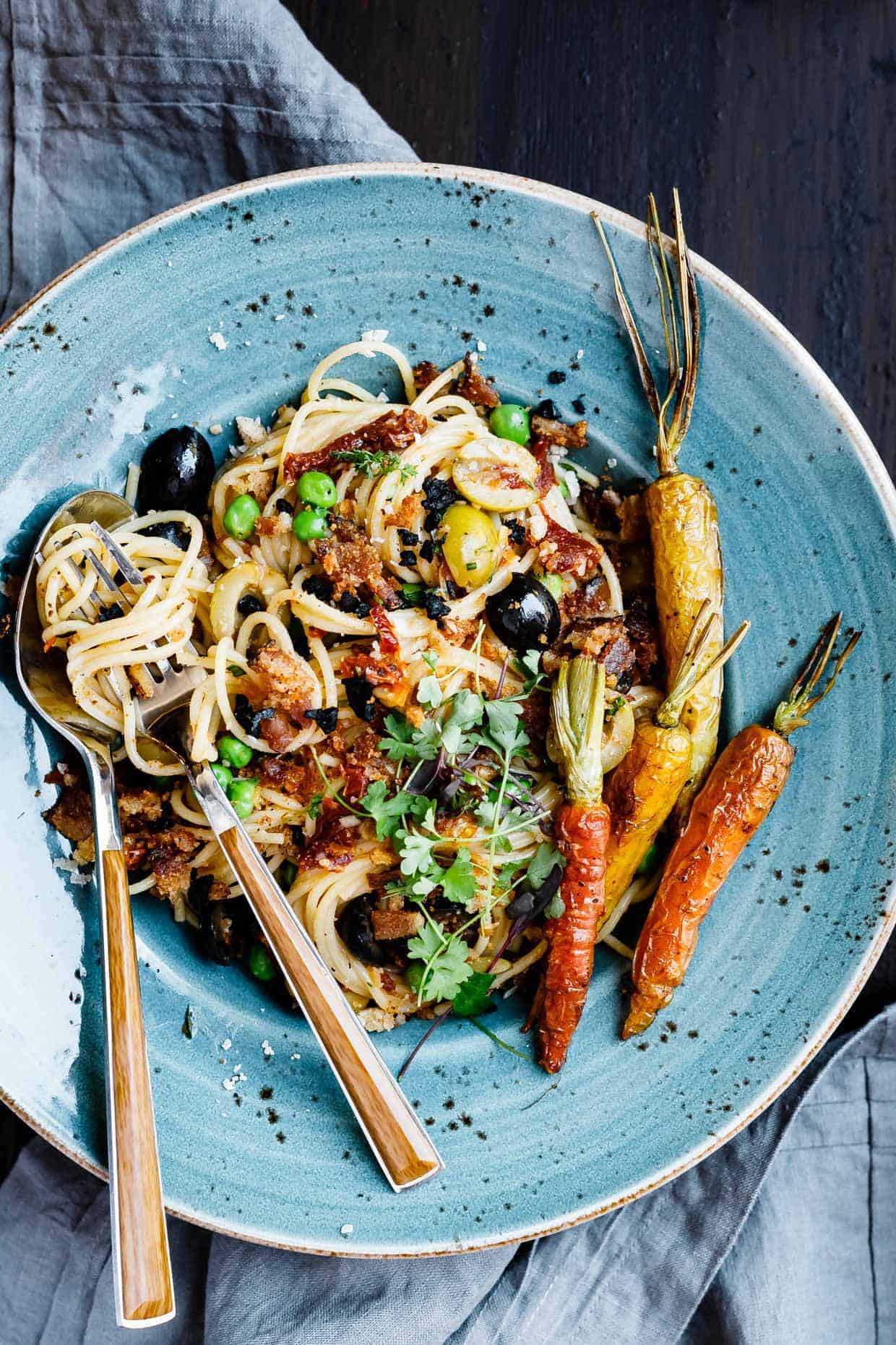 Brown butter shallot pasta with roasted carrots, fresh peas, bacon breadcrumbs, and dehydrated olives.