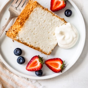 gluten free angel food cake on plate with whipped cream and fruit