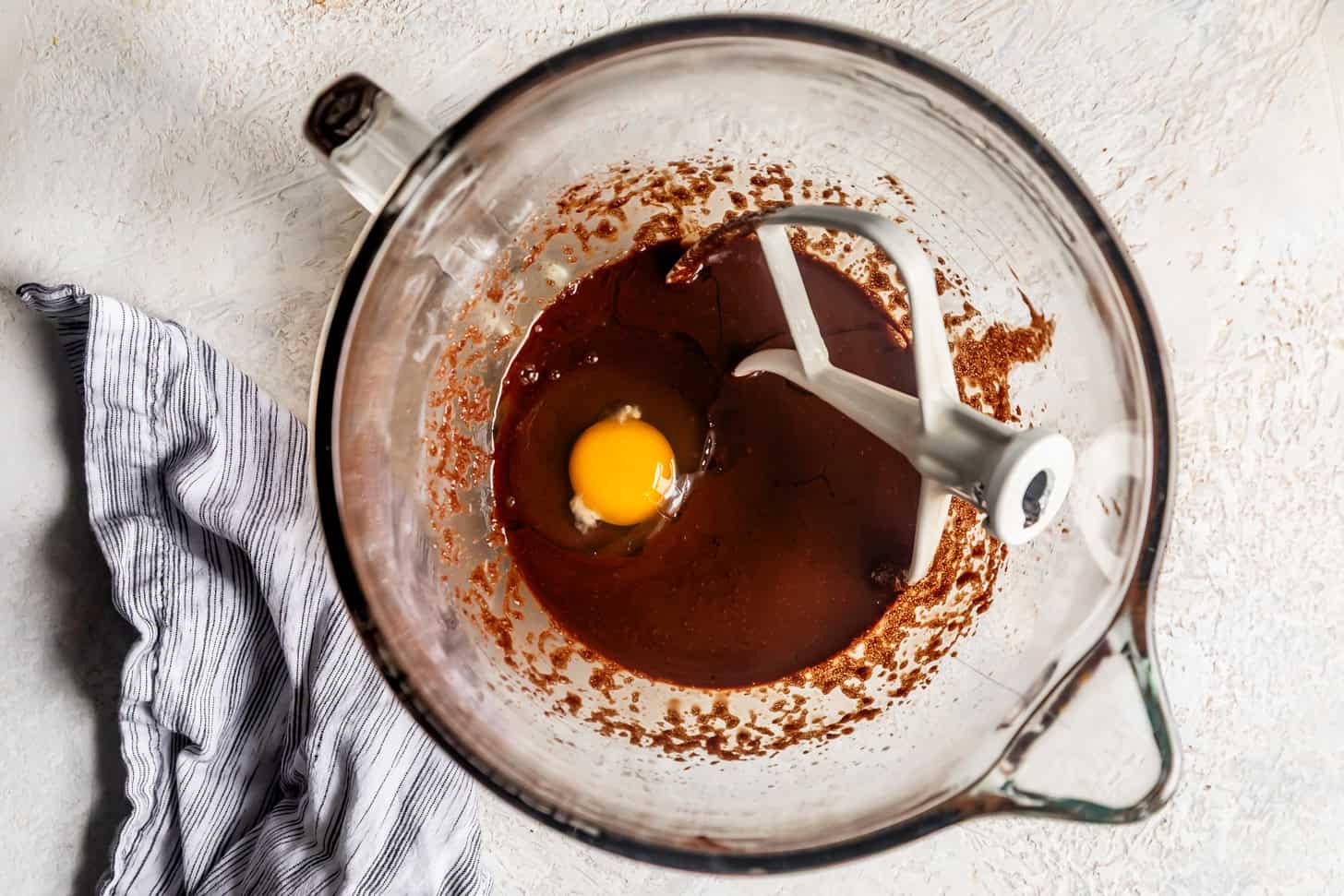 Adding eggs to brownie batter in mixer bowl