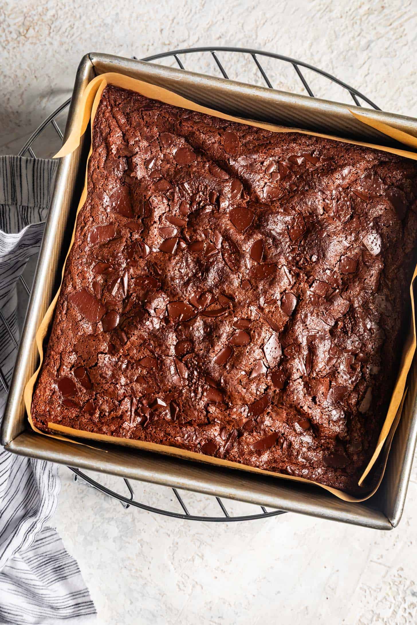 Crackly mochi brownies with melted chocolate on top in baking pan