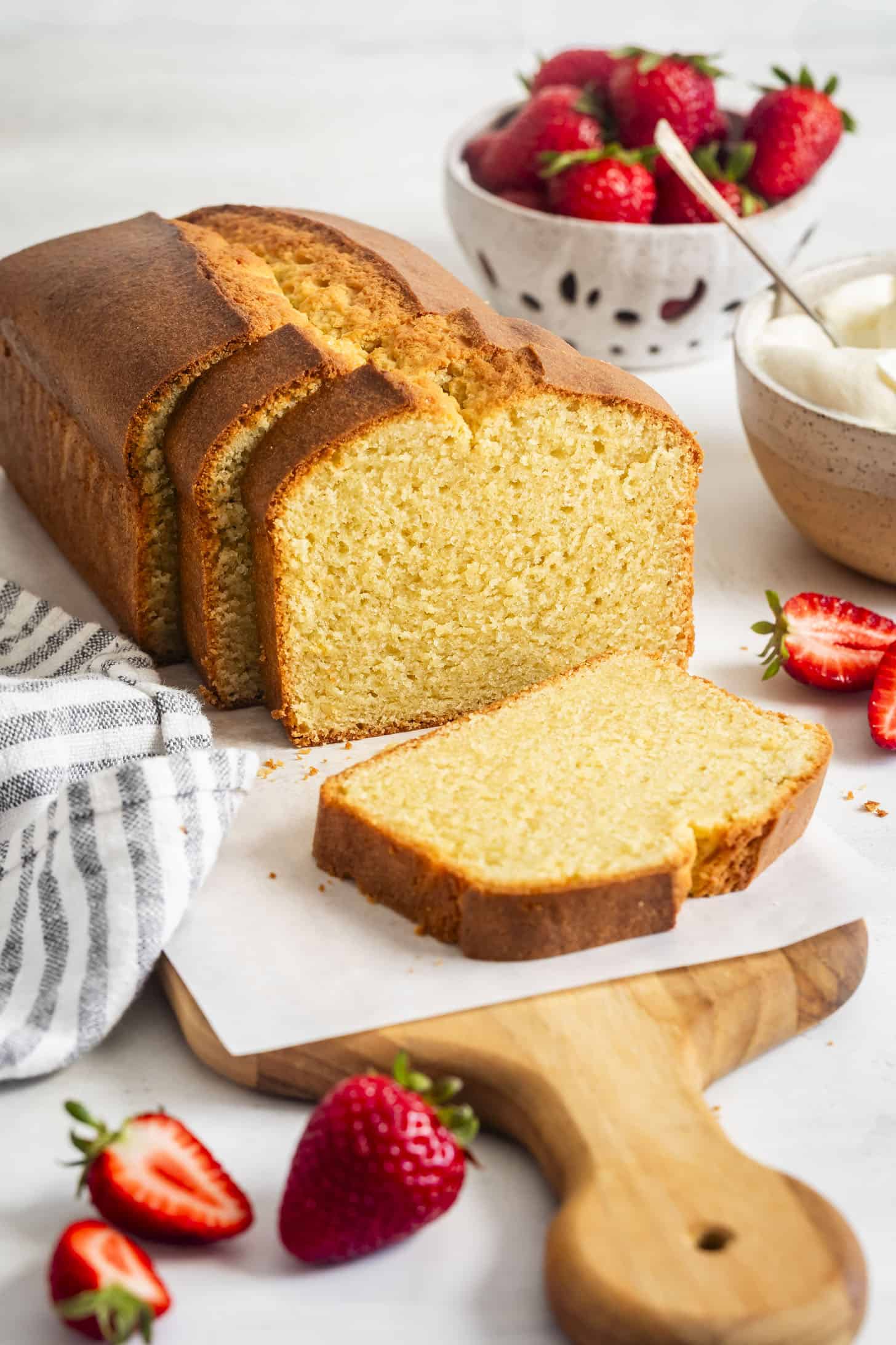Loaf of Almond Flour Gluten-Free Pound Cake with Slice on Cutting Board with Strawberries