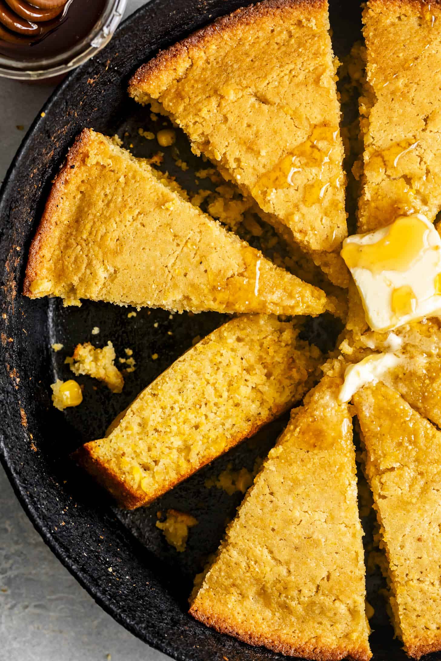 Sliced Gluten-Free Cornbread in Skillet with Butter and Honey