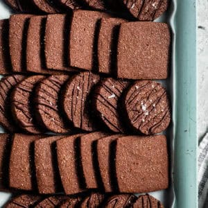 Rows of square and round chocolate cookies, some drizzled with chocolate and sprinkled with sea salt, are joined by classic No-Bake Peanut Butter Cookies for a delightful mix of textures and flavors.