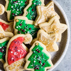 A plate of sprinkled and frosted gluten-free cut-out sugar cookies up close