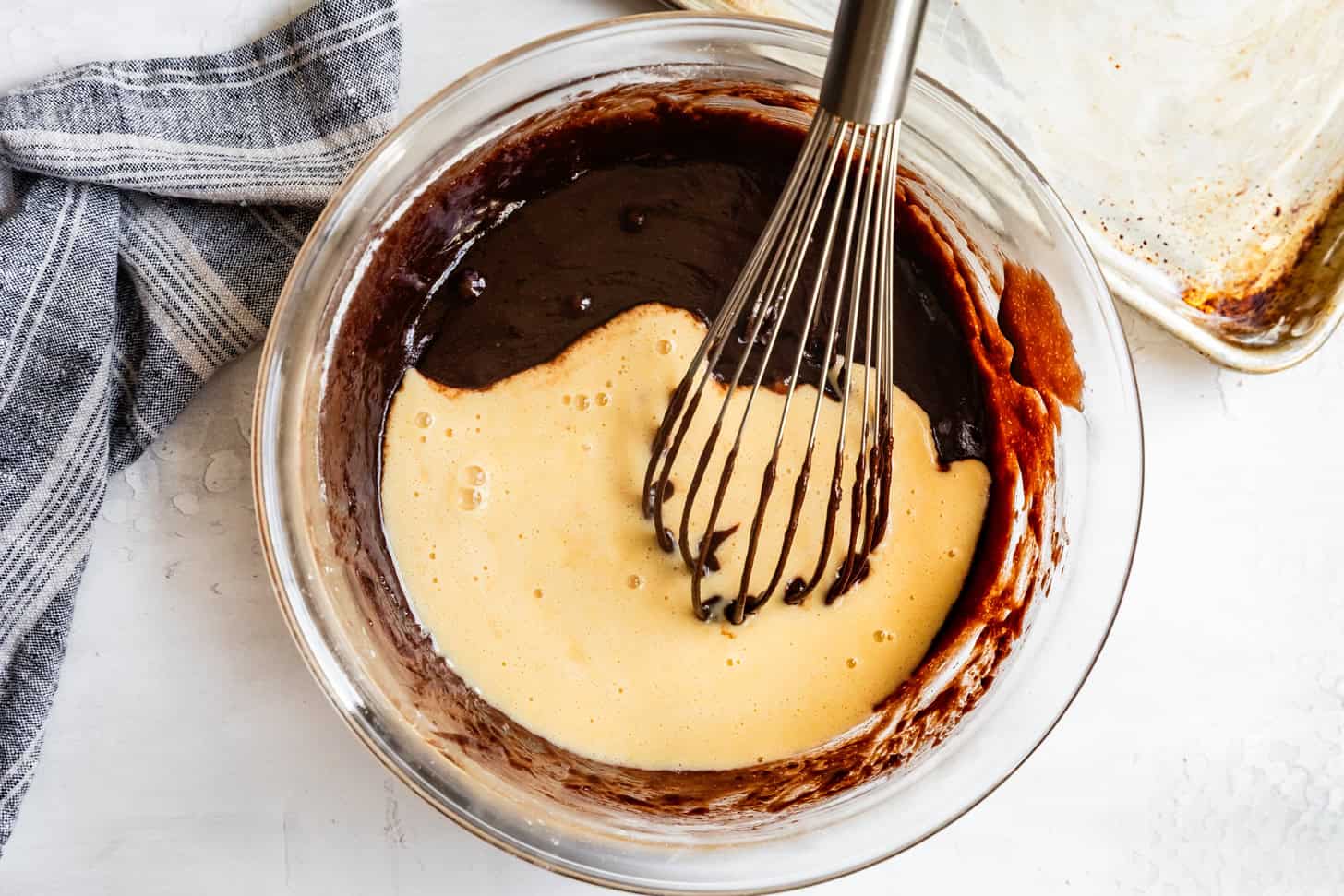 Pouring Buttermilk and Eggs into Chocolate Cake Batter in Glass Bowl with Whisk
