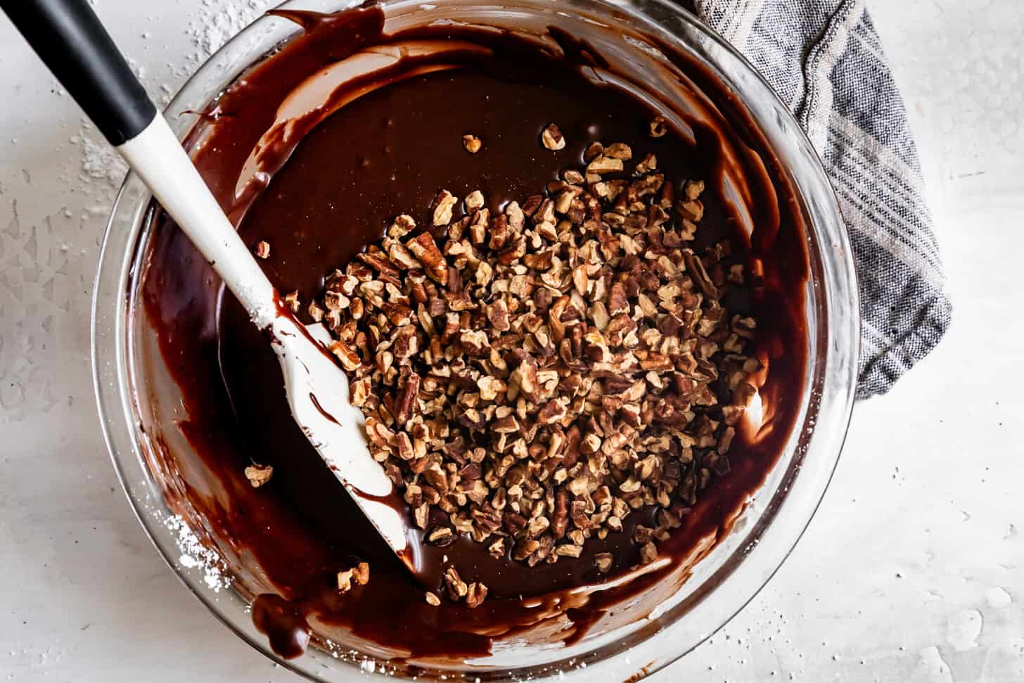 Adding Pecans Chocolate Fudge Icing in Glass Bowl with Spatula