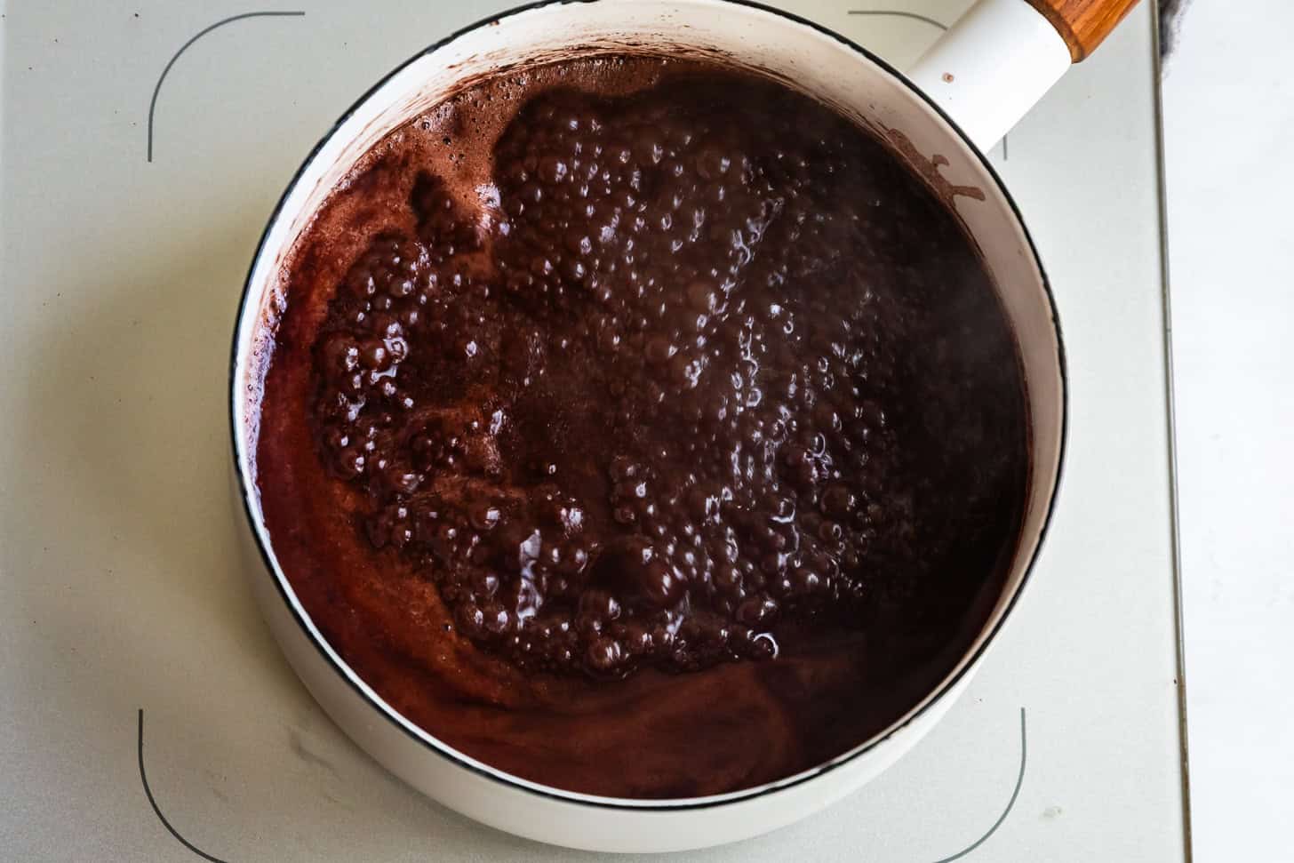 Boiling Cocoa and Butter in White Saucepan for Texas Sheet Cake