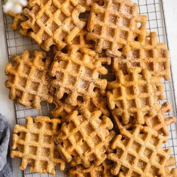 Golden brown sugar mochi waffles dusted with powdered sugar, stacked on a cooling rack