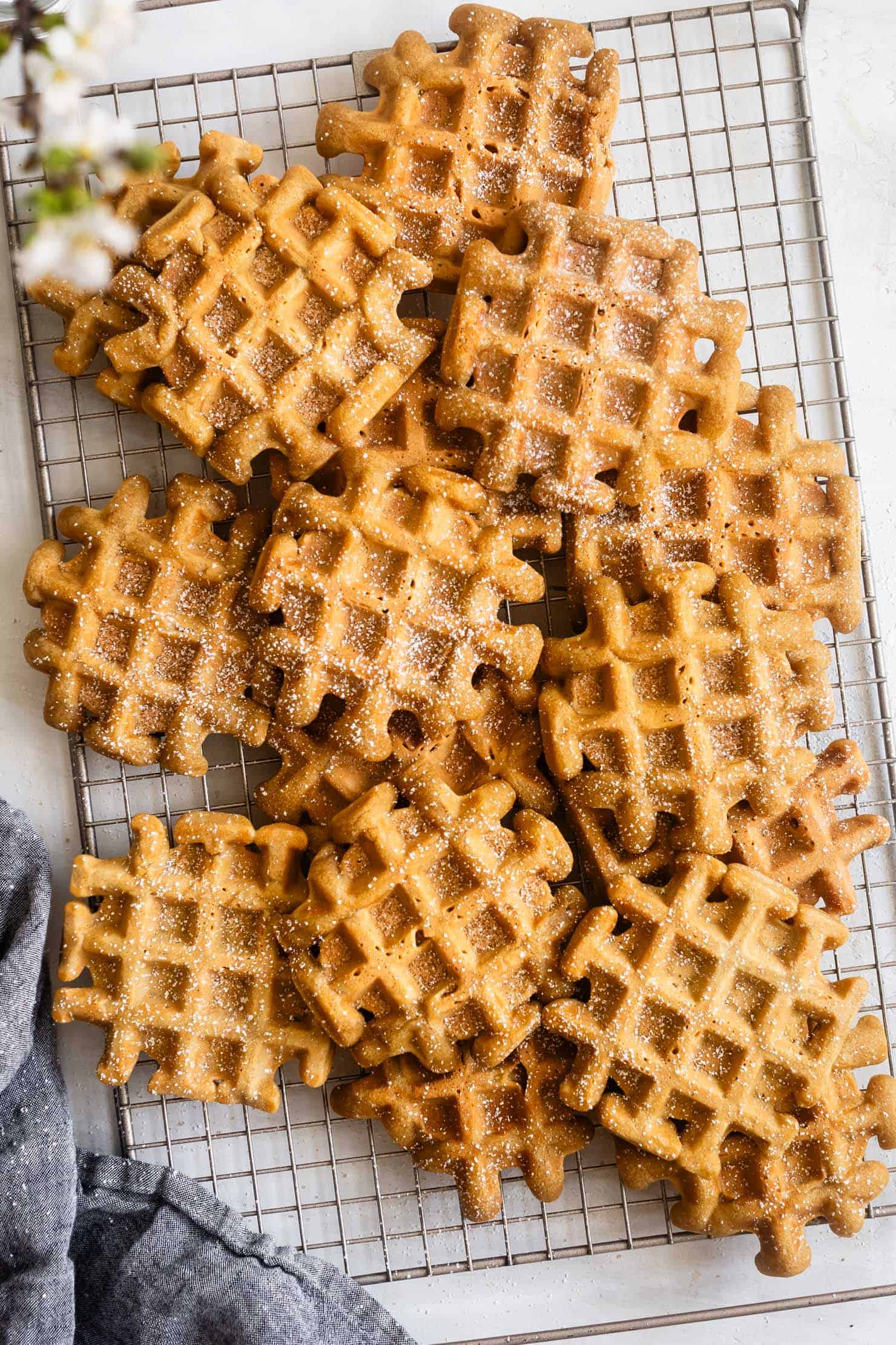 Golden brown sugar mochi waffles dusted with powdered sugar, stacked on a cooling rack