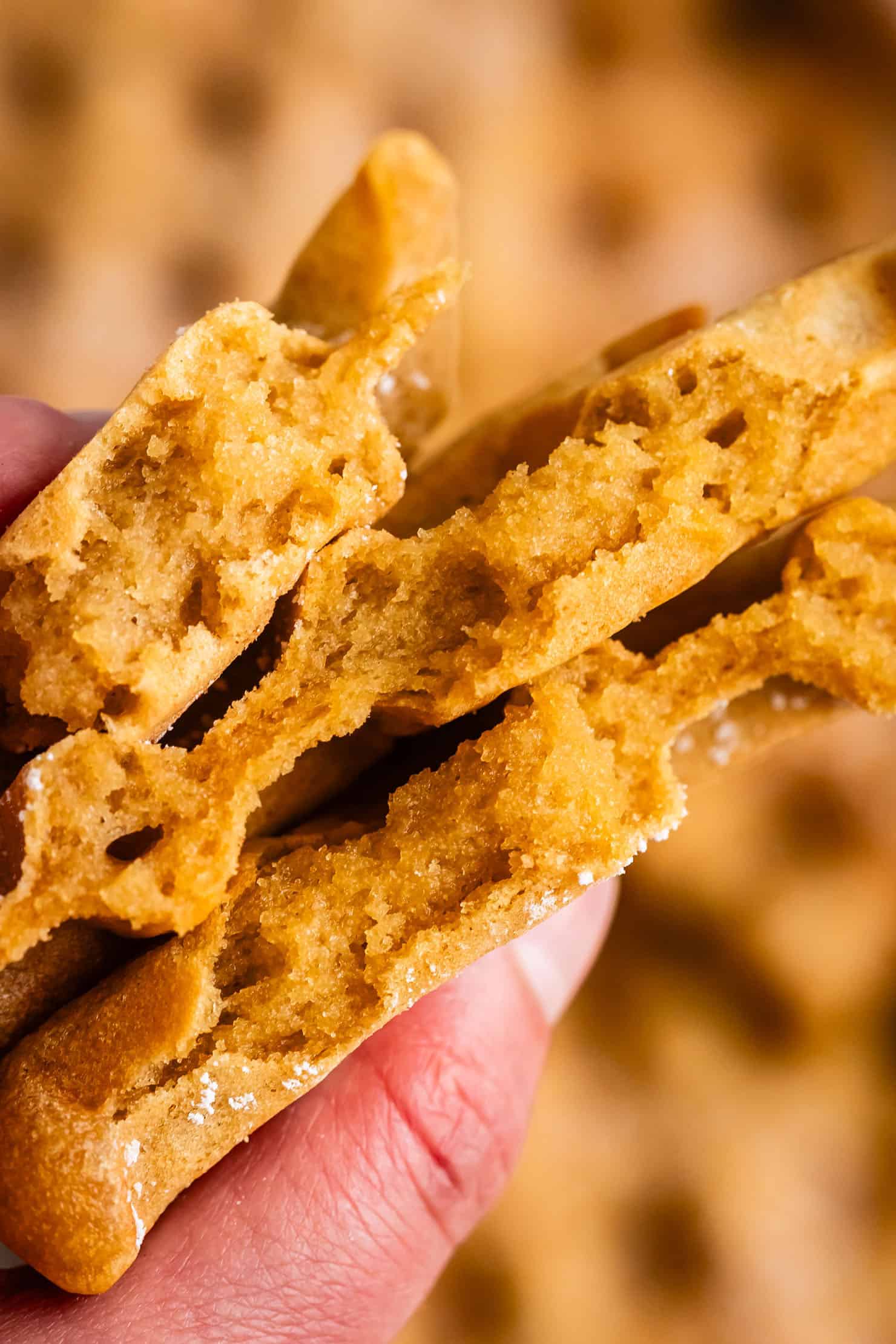 A hand holding gooey, chewy mochi waffles broken in half