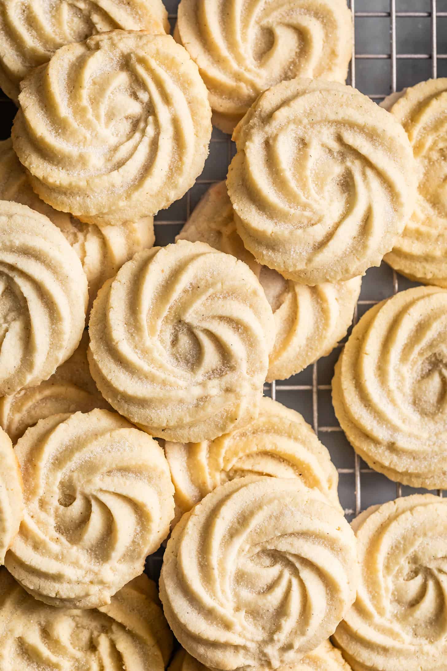 Swirled gluten-free butter cookies made with almond flour are piled on a cooling rack, lightly dusted with sugar.
