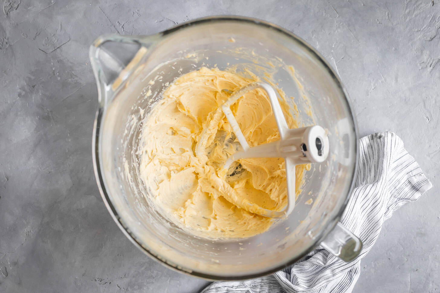 Creaming butter for gluten-free butter cookies in a glass mixing bowl with a paddle attachment.